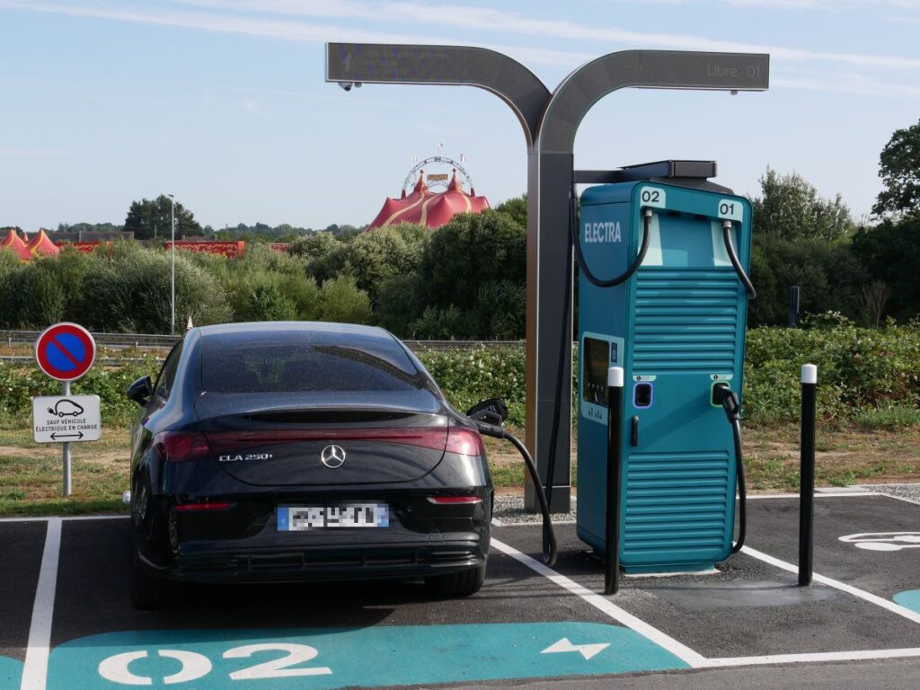 schwarzes Auto an türkisfarbener Ladesäule mit großem Display